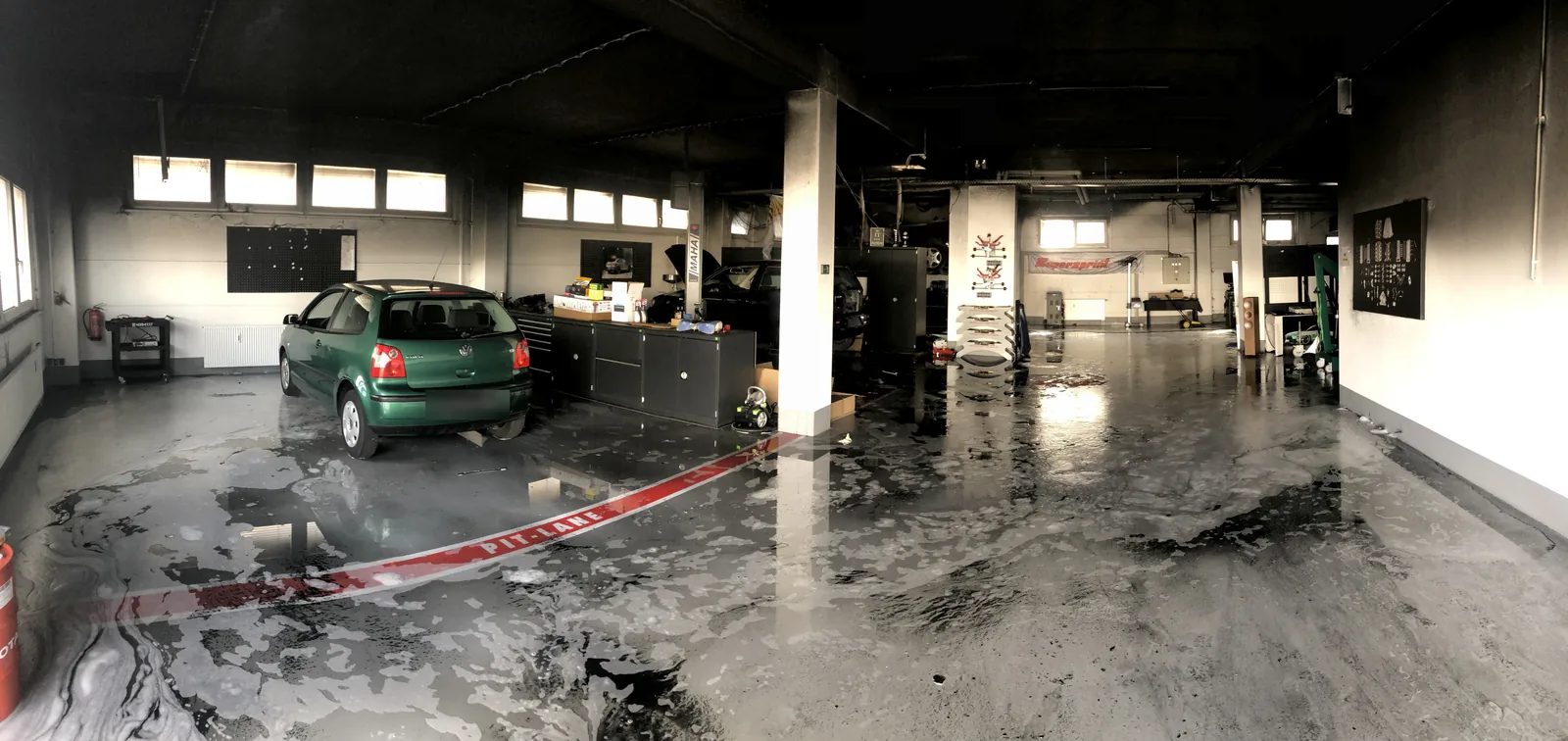 Blick in die ganze Werkstatthalle nach dem Brand, Löschschaum auf dem Boden